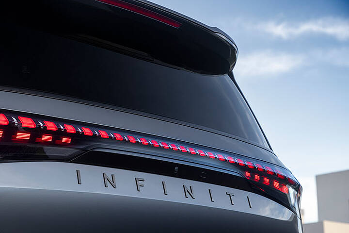 A close-up of the INFINITI nameplate decal under the taillights on a silver 2025 INFINITI QX80.